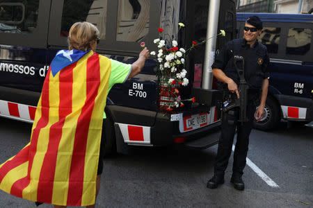 A woman wearing an Estelada (Catalan separatist flag) places a carnation on a Mossos d'Esquadra vehicle after a gathering in support of the banned October 1st independence referendum in Barcelona, Spain, September 24, 2017. REUTERS/Susana Vera