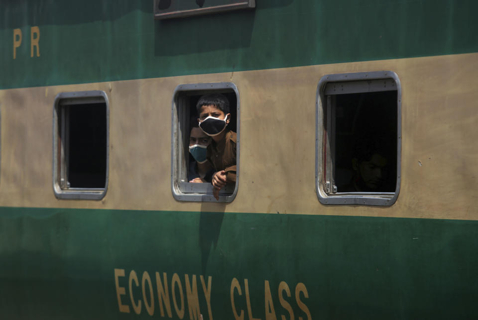 Boys wearing protective masks to help curb the spread of the coronavirus, look out the window of a train at a railway station, in Karachi, Pakistan, Saturday, Jan. 6, 2020. (AP Photo/Fareed Khan)