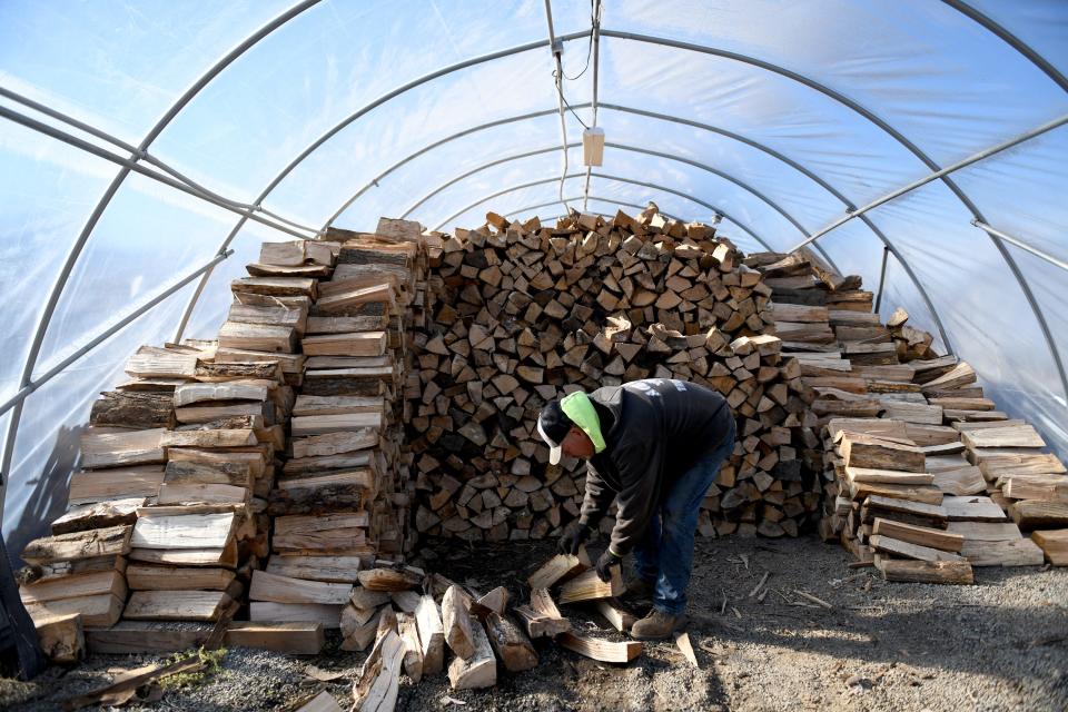 Dave West stacks wood for winter as the Christmas season gets underway at Planted Roots Garden Center in Plain Township.