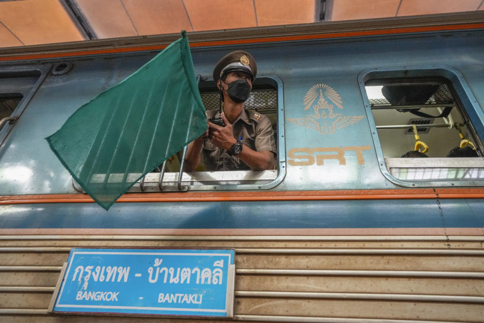 A train conductor waves the green flag signaling he's ready for departure from Hua Lamphong railway station in Bangkok, Thailand, Tuesday, Jan. 17, 2023. As Thailand officially opened what is said to be Southeast Asia's largest train station in Bangkok, Thursday, Jan. 19, 2023, the century-old iconic station will still be used for local operations for the time being. (AP Photo/Sakchai Lalit)