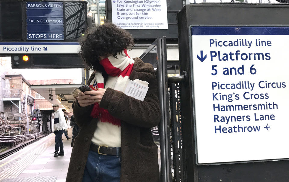 A man covers his face with a football scarf as he waits at a tube station in London, Friday, March 13, 2020. For most people, the new coronavirus causes only mild or moderate symptoms, such as fever and cough. For some, especially older adults and people with existing health problems, it can cause more severe illness, including pneumonia. (AP Photo/Kirsty Wigglesworth)