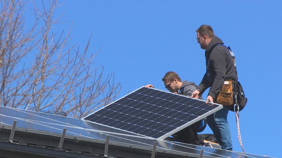 Workers from another company inspect the problems with Sarah D’Apollonia's solar panels on her Dartmouth home. 