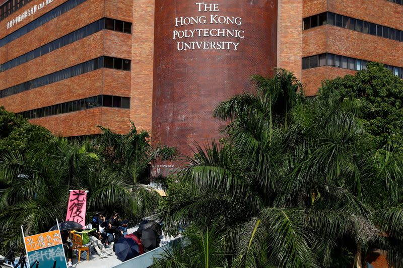 FILE PHOTO: Protesters sit at a barricade set up on the roof of a footbridge leading to the Hong Kong Polytechnic University