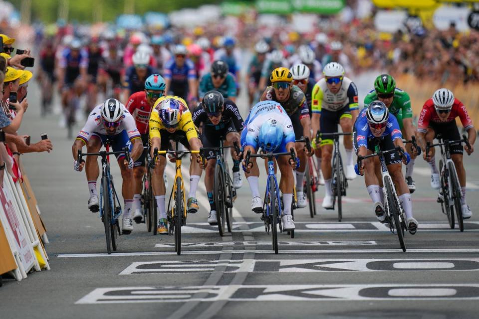 Dylan Groenewegen, centre, lunges to victory by the width of a tyre (AP)