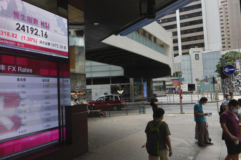 People wearing face masks stand in front of a bank's electronic board showing the Hong Kong share index at Hong Kong Stock Exchange in Hong Kong Monday, Sept. 27, 2021. Asian share rose Monday, but skepticism about the economic outlook for the region tempered the rally amid worries about further waves of COVID-19 outbreaks. (AP Photo/Vincent Yu)