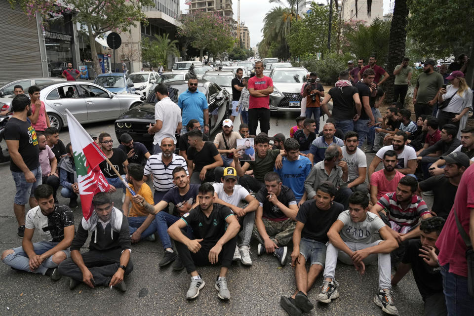 Protesters sit on the ground to block a road near the Justice Palace during a demonstration demanding the release of two people arrested last week during a bank robbery, in Beirut, Lebanon, Monday, Sept. 19, 2022. Anger with local lenders who have been imposing informal capital controls including limits on ATM withdrawals for nearly three years increased in recent weeks, with some depositors storming bank branches and taking their trapped savings by force. (AP Photo/Bilal Hussein)