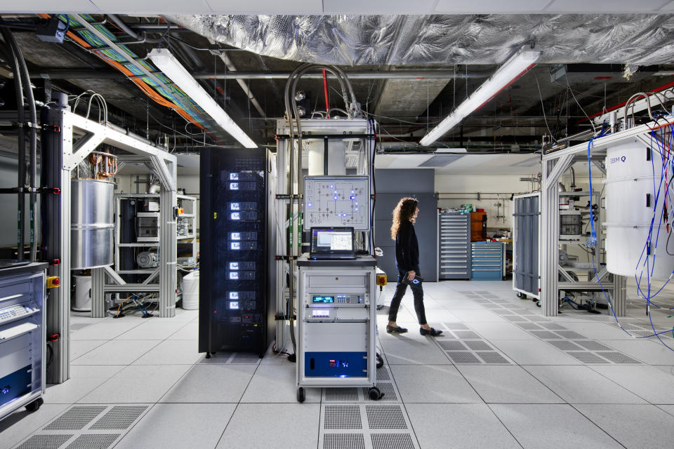 A woman walking through an IBM data center surrounded by equipment.