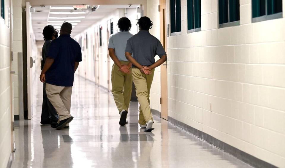 Residents keep their hands behind their backs as they walk down a hallway to a classroom at the Mecklenburg County Juvenile Detention Center on Friday, May 27, 2022. The state is urging commissioners and Sheriff Garry McFadden to reconsider a budget item that proposes closing the center on Spector Drive in Charlotte, NC.