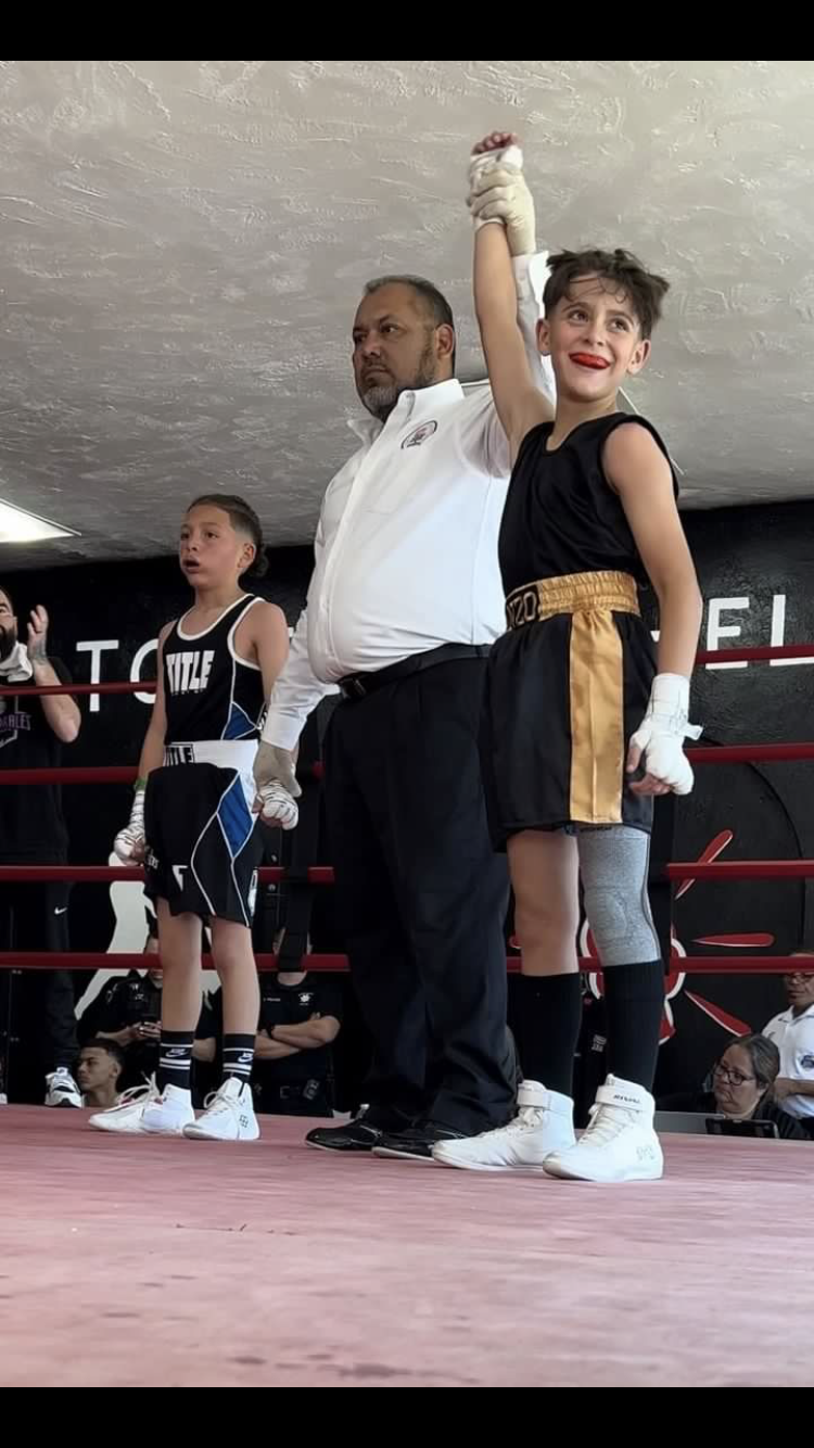 Turtle Bay School sixth grader Diego "El Gallito" Manzo fighting out of Shasta Boxing Club (right) gets his hand raised in victory after defeating Isaac Quintanilla of Jose Morales Boxing Gym (left) on Saturday, April 15, 2023.