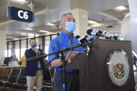 With Hawaii Lt. Gov Josh Green, left, in the background, Hawaii Gov. David Ige speaks at a press conference at the Daniel K. Inouye International Airport Thursday, Oct. 15, 2020, in Honolulu. A new pre-travel testing program will allow visitors who test negative for COVID-19 to come to Hawaii and avoid two weeks of mandatory quarantine goes into effect Thursday. The pandemic has caused a devastating downturn on Hawaii's tourism-based economy. Coronavirus weary residents and struggling business owners in Hawaii will be watching closely as tourists begin to return to the islands. (AP Photo/Marco Garcia)