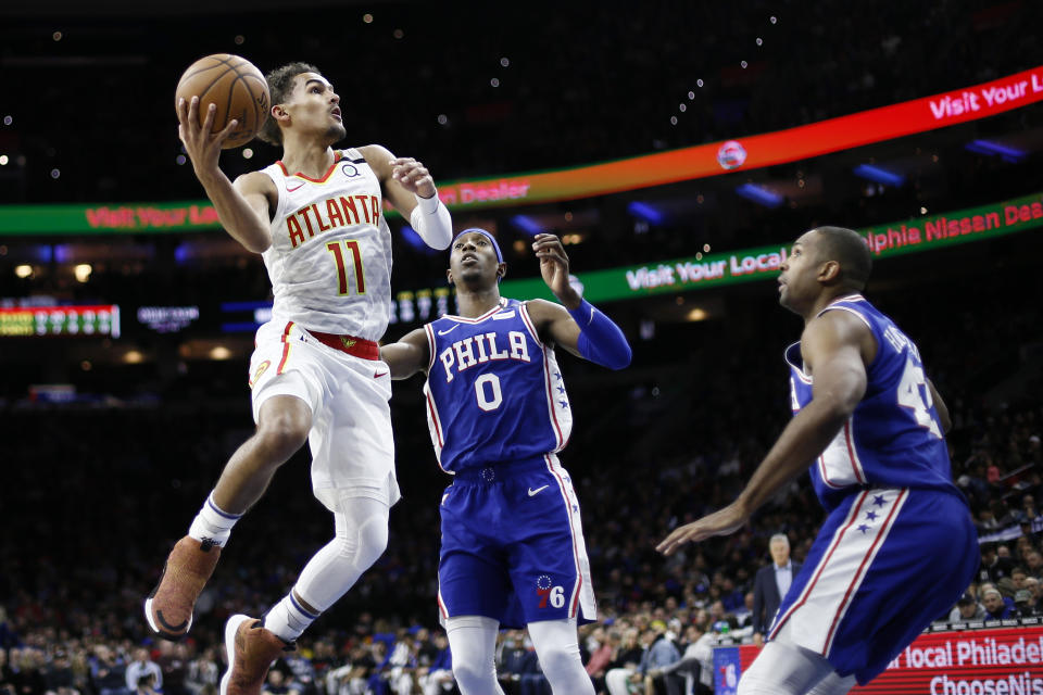 Atlanta Hawks' Trae Young, left, goes up to shoot against Philadelphia 76ers' Josh Richardson, center, and Al Horford during the first half of an NBA basketball game, Monday, Feb. 24, 2020, in Philadelphia. (AP Photo/Matt Slocum)