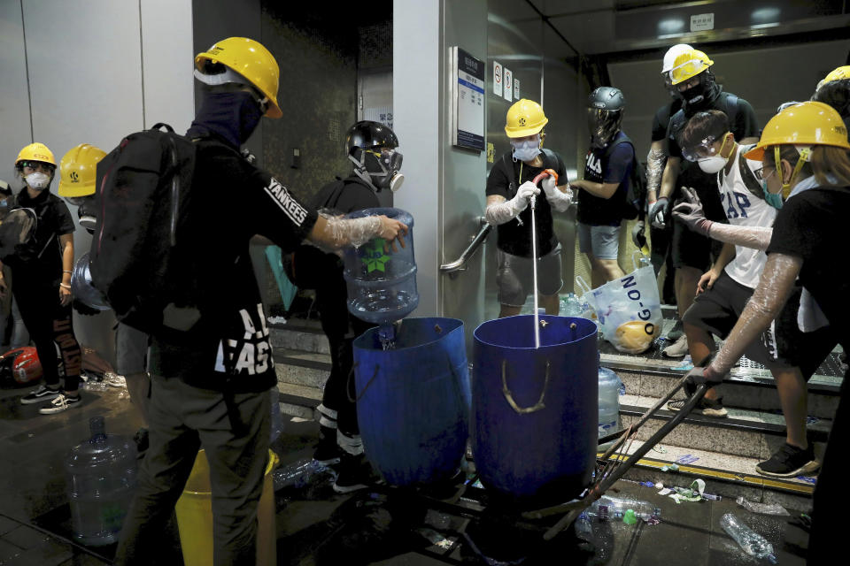 Protesters prepare water to toss at the tear gas canister as they face off with policemen during a protest against police brutality in Hong Kong, Sunday, July 28, 2019. Police fired tear gas at protesters in Hong Kong on Sunday for the second night in a row in another escalation of weeks-long pro-democracy protests in the semi-autonomous Chinese territory. (AP Photo/Vincent Yu)