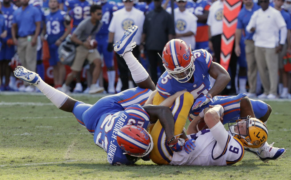 LSU quarterback Joe Burrow (9) is tackled by Florida defensive back Chauncey Gardner-Johnson (23) and defensive back CJ Henderson, right, after running for a first down during the first half of an NCAA college football game, Saturday, Oct. 6, 2018, in Gainesville, Fla. (AP Photo/John Raoux)