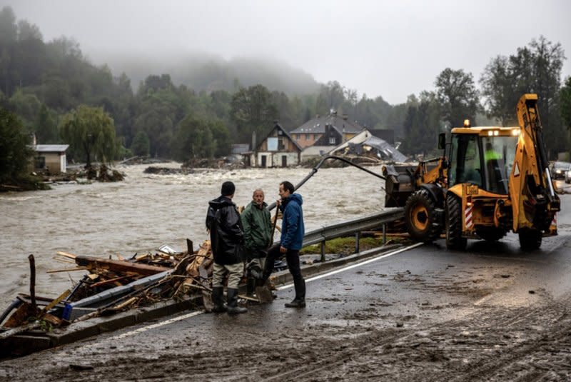 On Monday, local residents stand on a road with collapsed houses and the overflowing Bela River seen in the background after heavy rain in the town of Jesenik, Czech Republic. Photo Provided by Martin Divisek/EPA-EFE