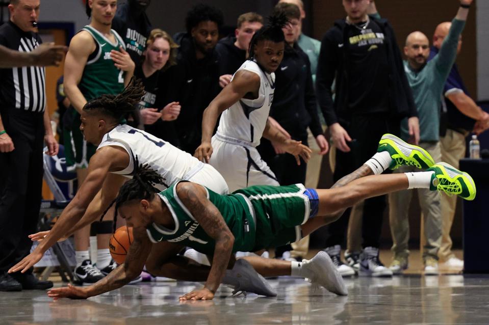 Jacksonville Dolphins forward DeeJuan Pruitt (1) and North Florida Ospreys guard Chaz Lanier (2) hit the floor chasing a loose ball during the second half of their game on Jan. 12 at UNF Arena. UNF defeated JU 82-74.