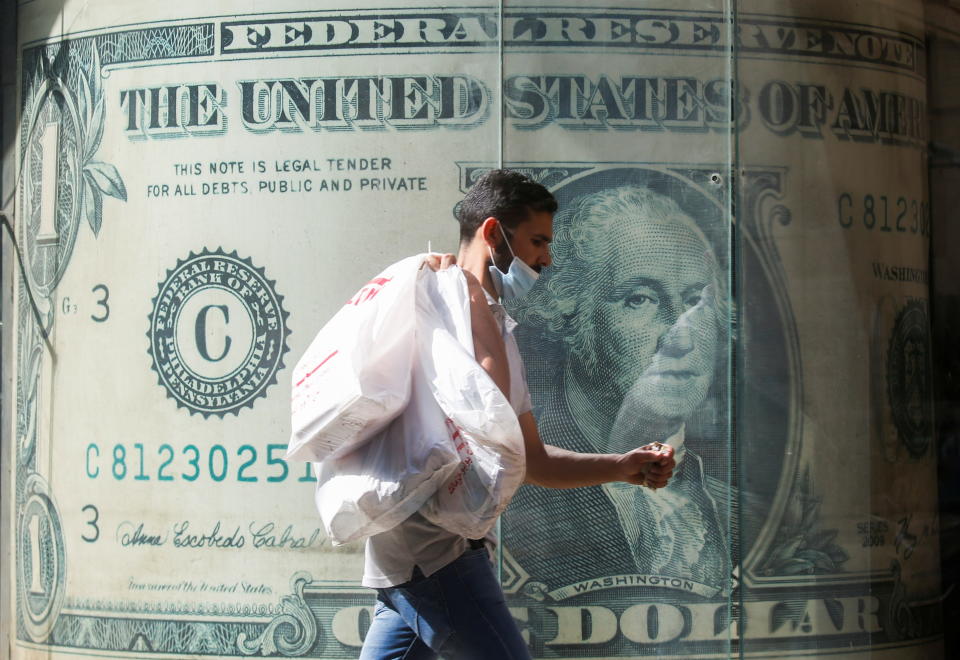 A man wearing a protective face mask walks in front of a currency exchange bureau advertisement showing an image of the U.S. dollar amid the coronavirus disease (COVID-19) pandemic in Cairo, Egypt May 5, 2021. REUTERS/Amr Abdallah Dalsh