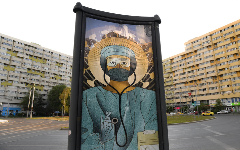A depiction of a medical staff wearing protective equipment, executed in the style of Christ Pantocrator, is placed at an intersection, in Bucharest, Romania, Wednesday, April 29, 2020. The artwork, among others depicting medical staff in the manner of religious icons, created by designer Wanda Hutira, is part of a campaign called Thank You Doctors, meant to raise awareness to the work of medical staff fighting the COVID-19 pandemic. Following public pressure by Romania's influential Orthodox church the artworks, described as "blasphemous", will be removed from all locations in the Romanian capital, according to the agency behind the project. (AP Photo/Andreea Alexandru)