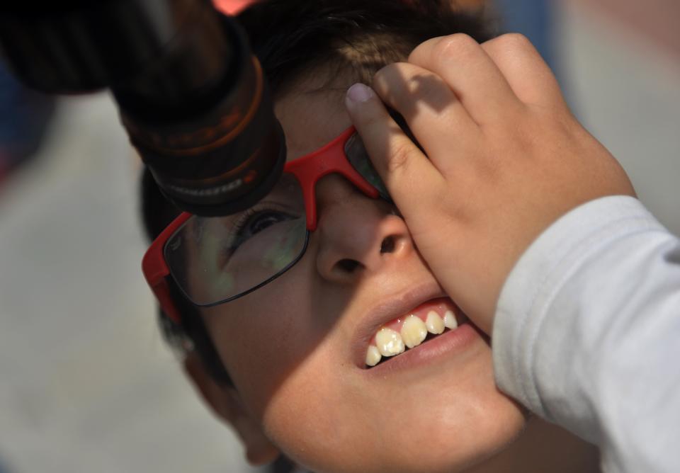 A Mexican boy looks through a telescope at the beginning of the solar eclipse, at the esplanade of the Museum of Natural History in Mexico City.&nbsp;