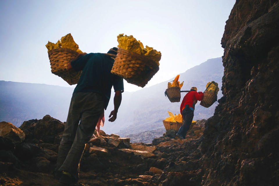 Miners carry loads of solidified sulfur