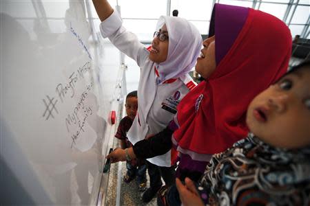 Women leave messages of support and hope for the passengers of the missing Malaysia Airlines flight MH370 at the Kuala Lumpur International Airport March 11, 2014. REUTERS/Damir Sagolj