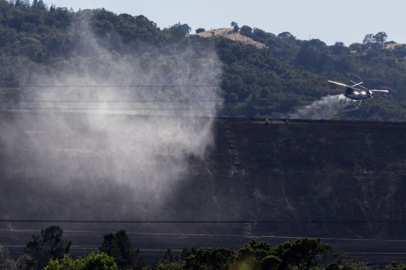 A cloud of water mist floats over the Lake Sonoma Dam after a helicopter refilled its tank from the lake to fight the Point Fire, west of Geyserville, Calif., on Sunday. Photo by Peter DaSilva/UPI