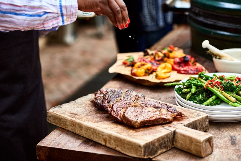 A woman seasons a steak