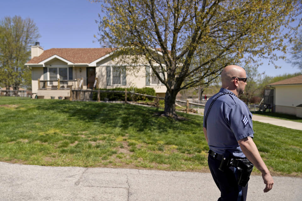 A police officer on April 17, 2023, walks past the house where 16-year-old Ralph Yarl was shot when he went to the wrong address to pick up his younger brothers in Kansas City, Mo. (Charlie Riedel / AP)