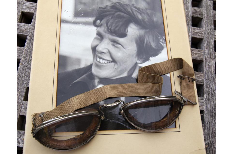 An original, unpublished personal photo of Amelia Earhart dated 1937, along with goggles