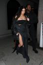 <p>In a bandeau top, asymmetrical pinstriped dress with a thigh-high slit, a puffer jacket, Calabasas necklace, and Yeezy boots while out in LA.</p>