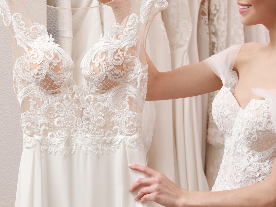 bride holding a wedding dress on a hanger