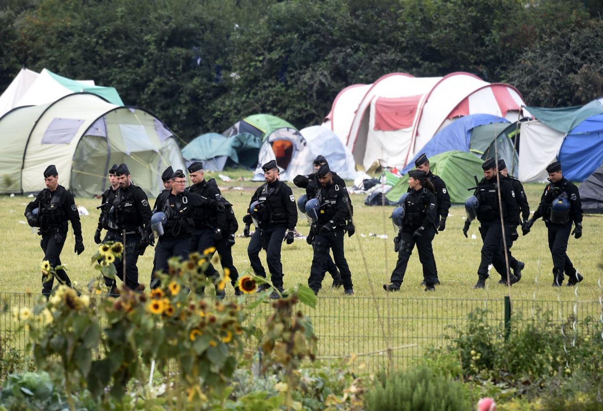 French riot police walk by tents during the evacuation of the Grande-Synthe migrant camp