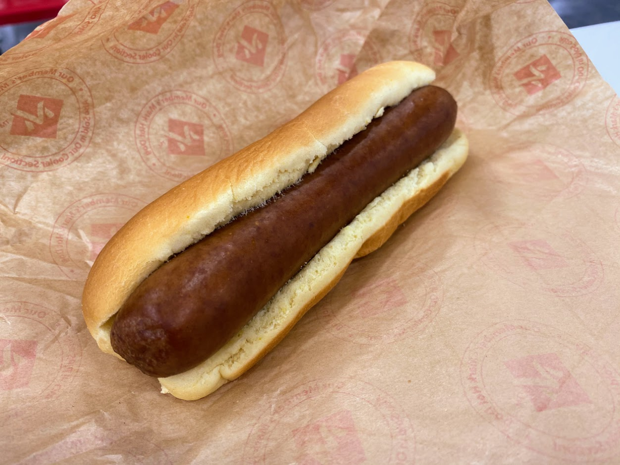 Sam's Club hot dog, plain, on brown paper, white table in the top right background