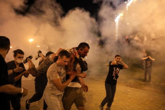 Protesters carry a man wounded during clashes with police in Belarus (AP)