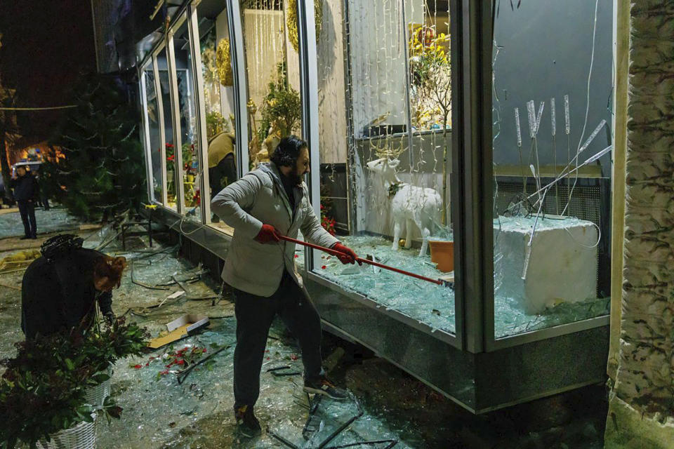 In this photo provided by Kharkiv Regional Administration, a man clears broken glass in a storefront after a Russian missile attack in Kharkiv, Ukraine, Sunday, Dec. 31, 2023. (Kharkiv Regional Administration via AP)