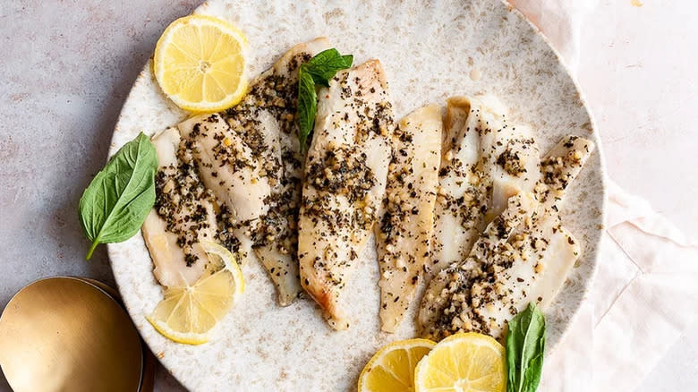 White fish fillets with crunchy topping, basil, and lemon slices