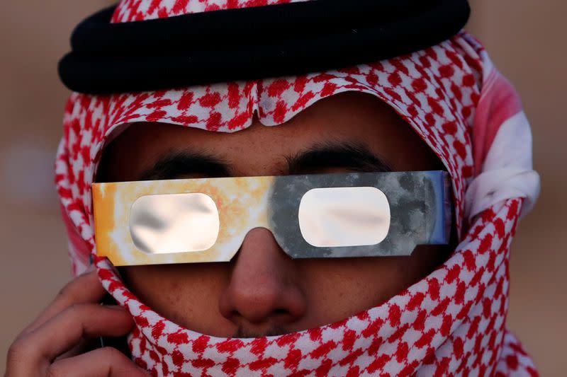 A Saudi man talks on his mobile phone as he monitors the annular solar eclipse on Jabal Arba (Four Mountains) in Hofuf