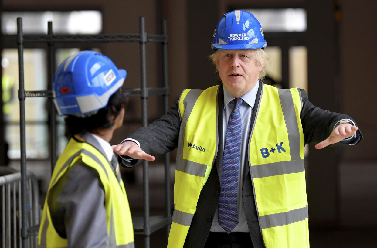Britain's Prime Minister Boris Johnson talks with year 10 pupil Vedant Jitesh during a visit to the construction site of Ealing Fields High School in west London, Monday June 29, 2020. (Toby Melville/Pool via AP)
