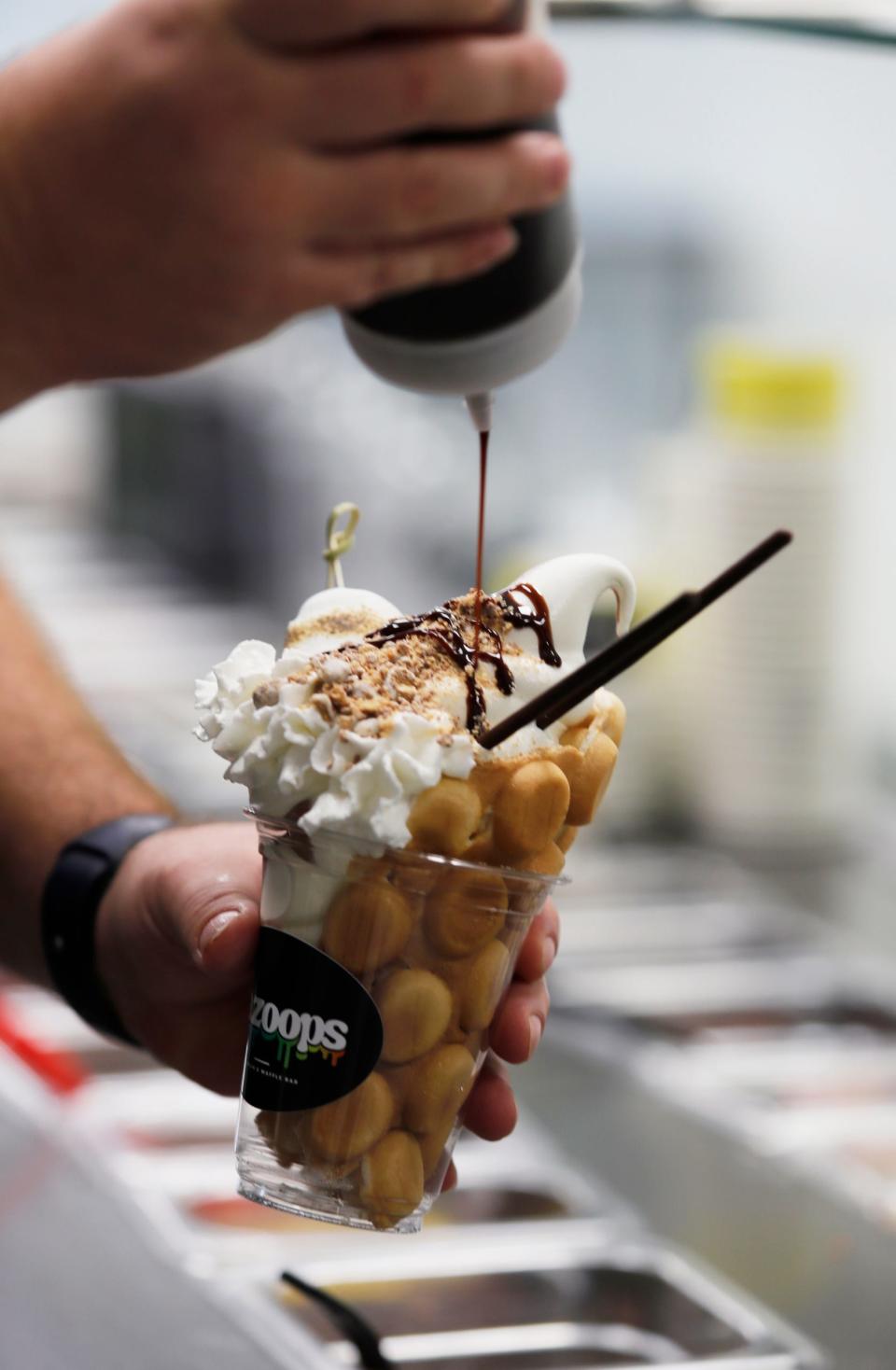 Darren Hussien, co-owner of Gazoops Ice Cream and Waffle Bar in Cape Coral, adds chocolate syrup while preparing a sample product.