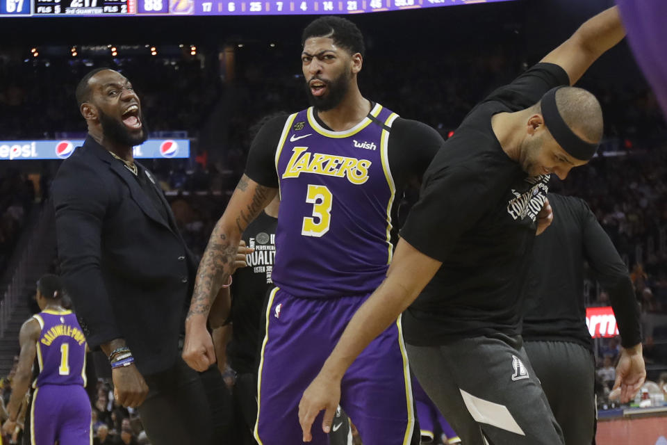 Los Angeles Lakers' LeBron James, left, celebrates with Anthony Davis (3) and Jared Dudley during the second half of an NBA basketball game against the Golden State Warriors in San Francisco, Thursday, Feb. 27, 2020. (AP Photo/Jeff Chiu)