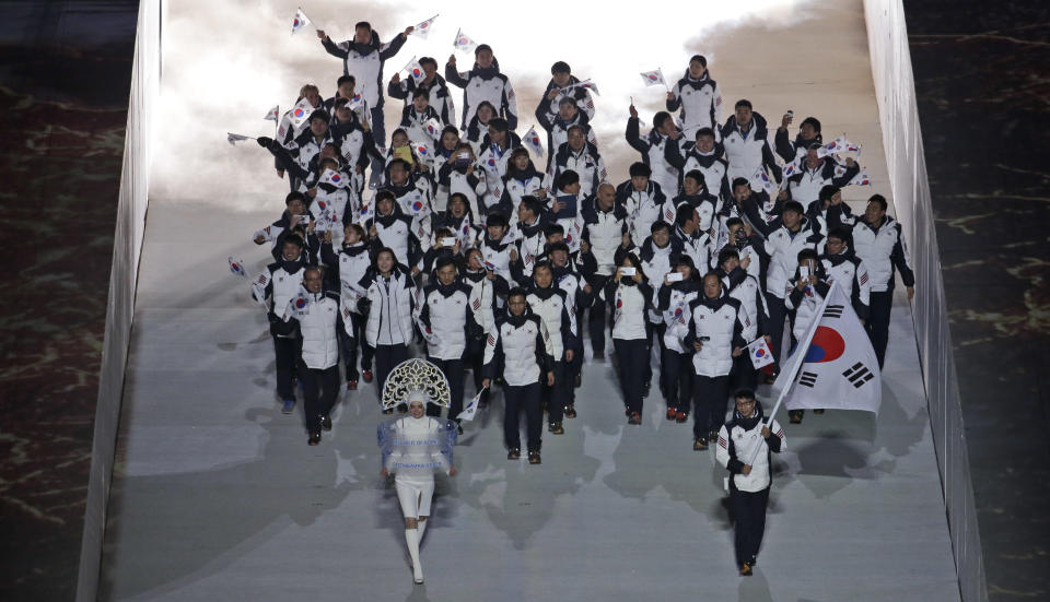 Lee Kyou-Hyuk of South Korea holds his national flag and enters the arena with teammates during the opening ceremony of the 2014 Winter Olympics in Sochi, Russia, Friday, Feb. 7, 2014. (AP Photo/Charlie Riedel)