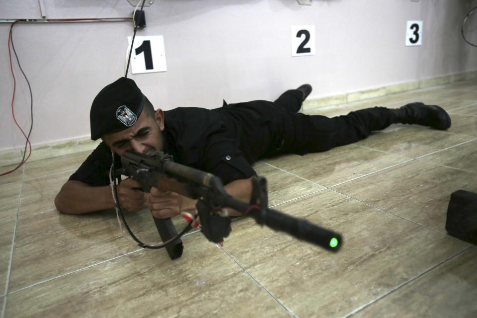 Palestinian security officer Muhmmad Debo, 22, fires an electronically-modified AK-47 rifle at the headquarters of the security training department of the Hamas interior ministry in Gaza City, in the northern Gaza Strip on Thursday, April 10, 2014. The laser-fitted rifles are a money saver that eliminates the need to train with live ammunition, which is in short supply in Gaza. (AP Photo/Adel Hana)