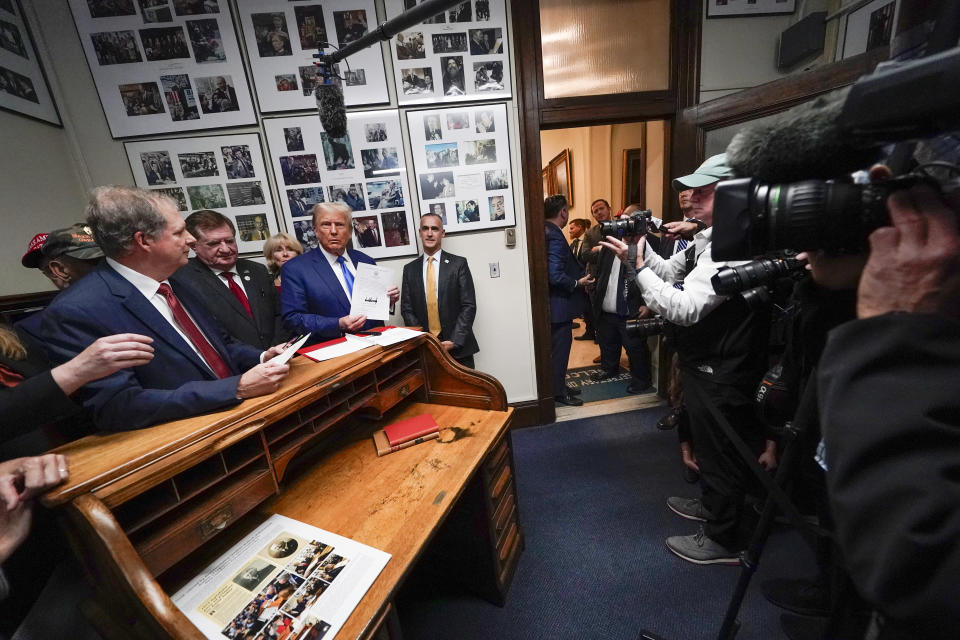 Republican presidential candidate former President Donald Trump talks as New Hampshire Secretary of State David Scanlan,left, listens as he signs papers to be on the 2024 Republican presidential primary ballot at the New Hampshire Statehouse, Monday, Oct. 23, 2023, in Concord, N.H. At right inside the doorway is Corey Lewandowski. (AP Photo/Charles Krupa)