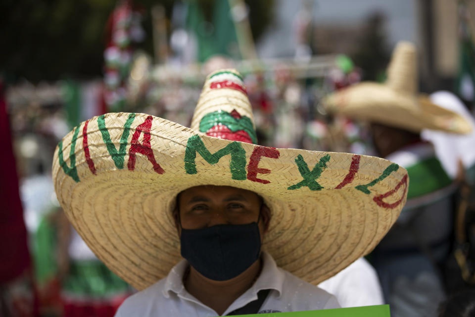 A souvenir vendor wearing a Mexican hat and a mask to curb the spread of the new coronavirus pushes his cart to a new location after authorities allowed the selling of patriotic souvenirs for the upcoming independence day celebration, further away from the city's downtown area as a precaution against the spread of COVID-19 in Mexico City, Wednesday, Sept. 2, 2020. (AP Photo/Fernando Llano)