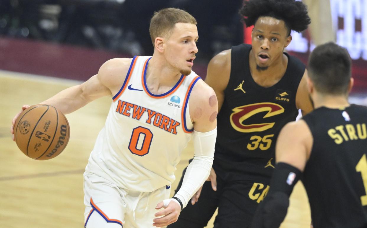 New York Knicks guard Donte DiVincenzo (0) dribbles beside Cleveland Cavaliers forward Isaac Okoro (35) on March 3 in Cleveland.