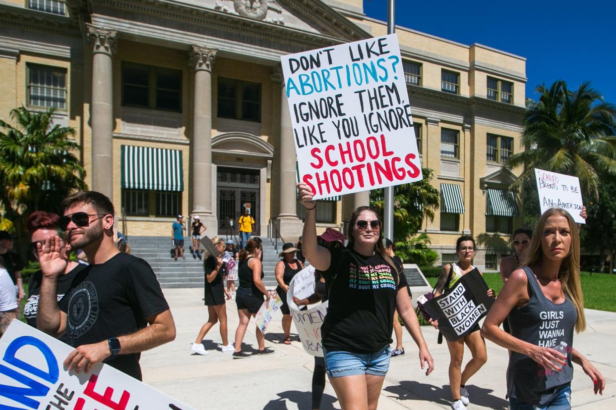 Kristin Gamble of Jupiter, center, holds a sign while walking towards the sidewalk during a protest held in front of the Palm Beach County Historic Courthouse in West Palm Beach on Sunday. Gamble said she was protesting because she didn’t want her daughters to have less rights than she or her mother did. Organized by Common Purpose Initiative, West Palm Beach Does Politics and other local groups, the event saw a group of about 50 gather to protest the recent United States Supreme Court decision to overturn Roe v. Wade.