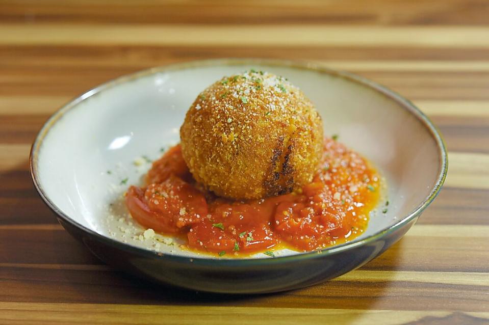 〈和牛炸飯糰〉是將西西里島街頭美食〈炸飯糰〉（Arancini）華麗升級，將陳年義大利米做的飯糰，以用牛骨髓與紅酒調味的和牛腿絞肉及馬茲瑞拉起司為內餡，風味與口感皆誘人。圖／姚舜