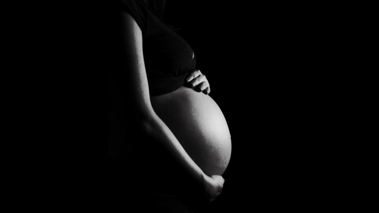 7 month pregnant belly isolated on a black background high contrast black white