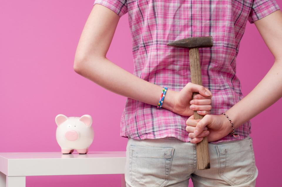 Someone approaching a piggy bank with a hammer behind their back.