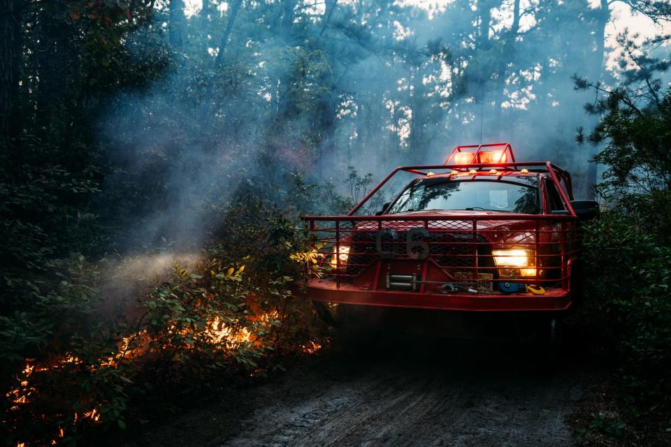 A New Jersey Forest Fire Service  vehicle travels on a pathway within a 200-acre Waterford wildfire in Wharton State Forest near the closed Atco Dragway early on August 21, 2023.