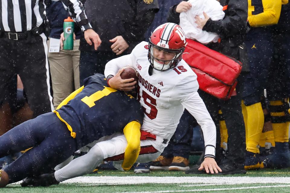 Oct 14, 2023; Ann Arbor, Michigan, USA; Indiana Hoosiers quarterback Brendan Sorsby (15) is tackled by Michigan Wolverines defensive back Amorion Walker (1) in the second half at Michigan Stadium. Mandatory Credit: Rick Osentoski-USA TODAY Sports